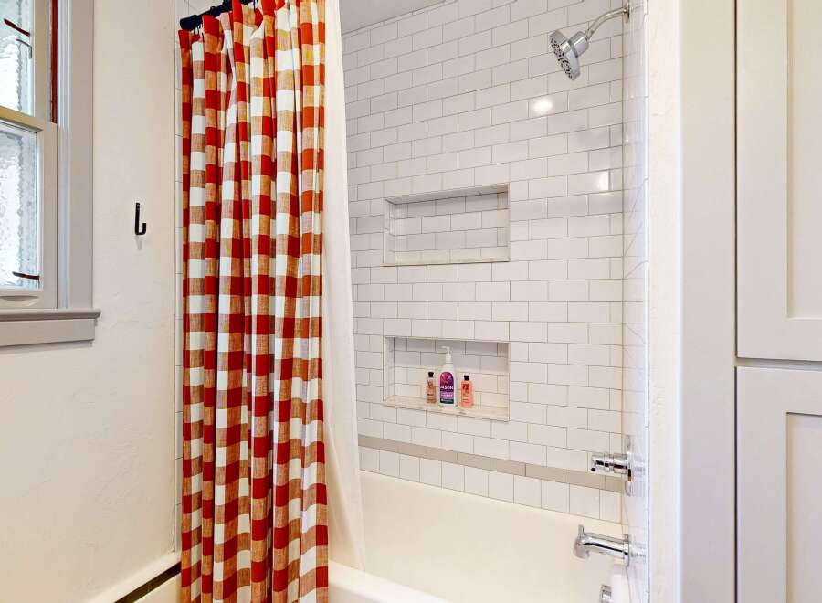 Step into this charming bathroom, featuring a stylish red and white checkered shower curtain that adds a pop of color.