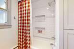 Step into this charming bathroom, featuring a stylish red and white checkered shower curtain that adds a pop of color.