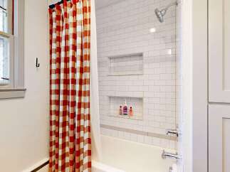 Step into this charming bathroom, featuring a stylish red and white checkered shower curtain that adds a pop of color.