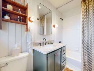 Step into this charming bathroom, featuring a stylish vanity with ample storage and a sleek countertop.