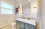 This charming bathroom features a stylish vanity with a marble countertop and elegant cabinetry.