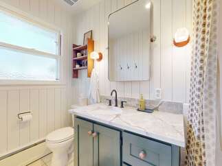 This charming bathroom features a stylish vanity with a marble countertop and elegant cabinetry.