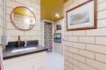 This charming bathroom features a unique design with a round mirror and a stylish vanity.
