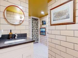 This charming bathroom features a unique design with a round mirror and a stylish vanity.