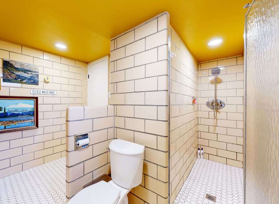 Step into a unique bathroom design featuring a vibrant yellow ceiling and classic tilework.