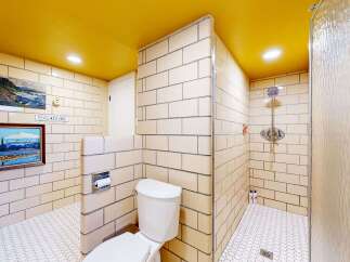 Step into a unique bathroom design featuring a vibrant yellow ceiling and classic tilework.