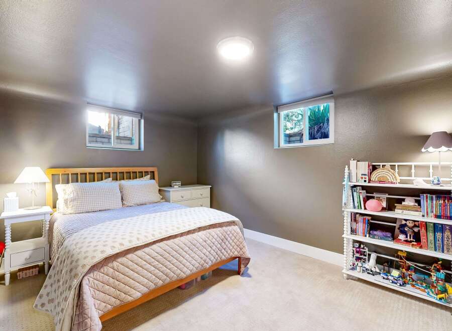 This cozy bedroom offers a serene retreat with its neutral color palette and ample natural light.