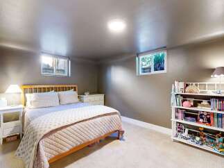 This cozy bedroom offers a serene retreat with its neutral color palette and ample natural light.