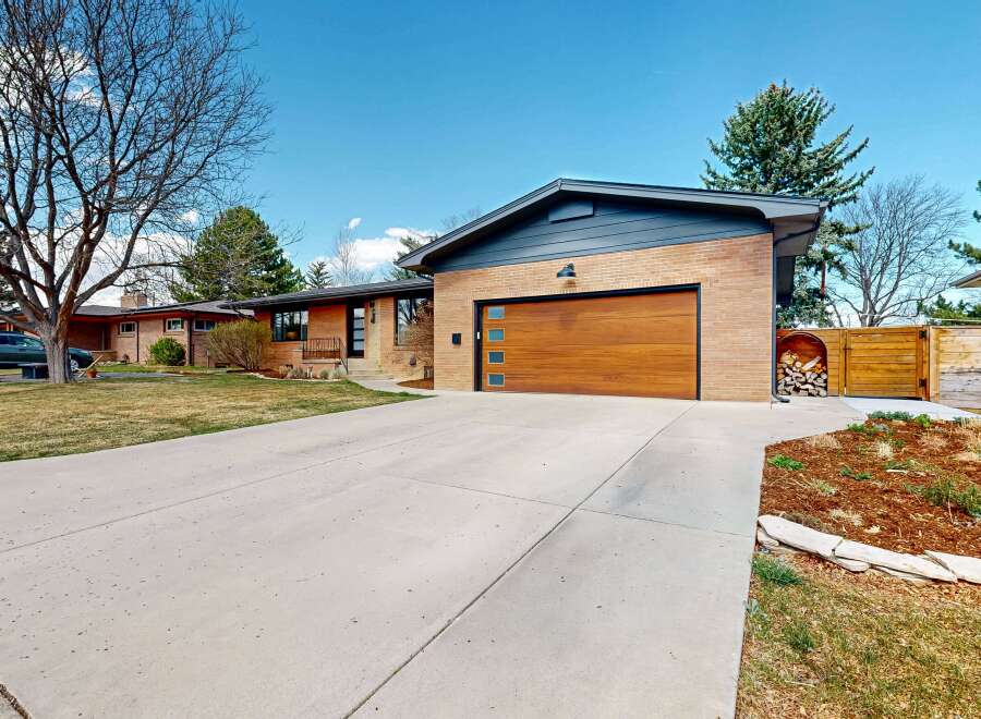 This stunning property boasts a modern design with a beautiful wooden garage door and a spacious driveway.
