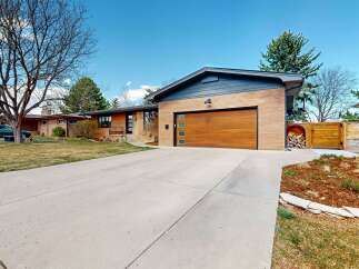 This stunning property boasts a modern design with a beautiful wooden garage door and a spacious driveway.