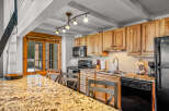 This stunning kitchen boasts beautiful wooden cabinetry, a sleek black appliance suite, and a gorgeous granite countertop.