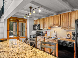 This stunning kitchen boasts beautiful wooden cabinetry, a sleek black appliance suite, and a gorgeous granite countertop.