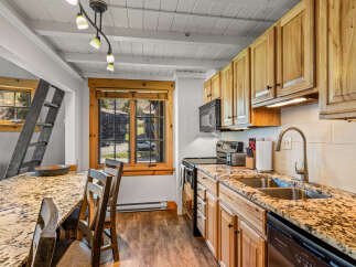 This charming kitchen boasts a rustic aesthetic with its wooden cabinetry and granite countertops.
