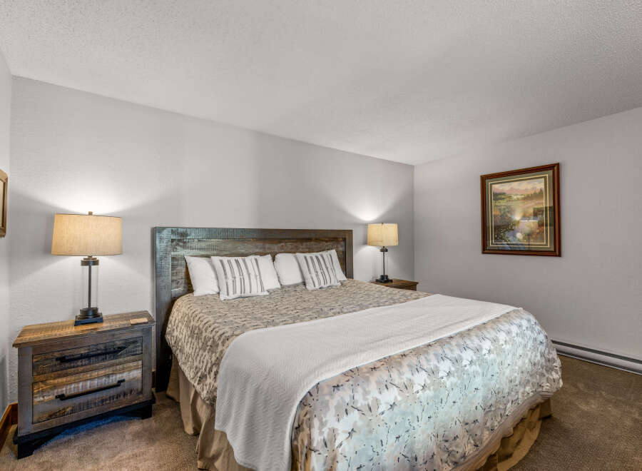 This cozy bedroom features a rustic wooden headboard and nightstands, creating a warm and inviting atmosphere.
