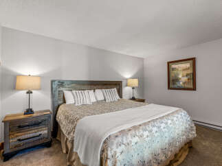 This cozy bedroom features a rustic wooden headboard and nightstands, creating a warm and inviting atmosphere.