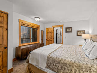 This inviting bedroom features a cozy ambiance with its warm wooden accents and neutral color palette.