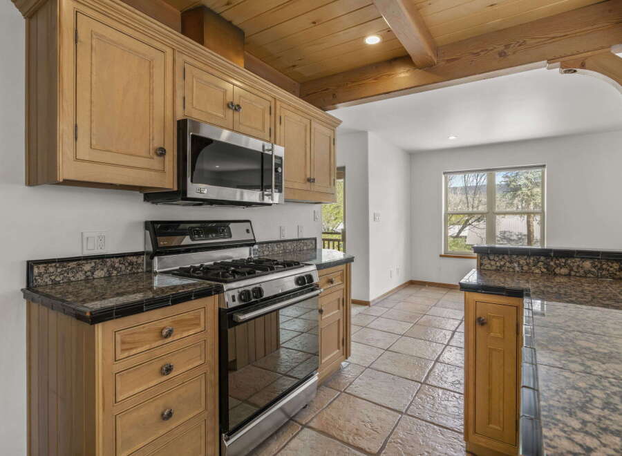 Step into this stunning kitchen, featuring beautiful wooden cabinetry and a modern stainless steel microwave and oven.