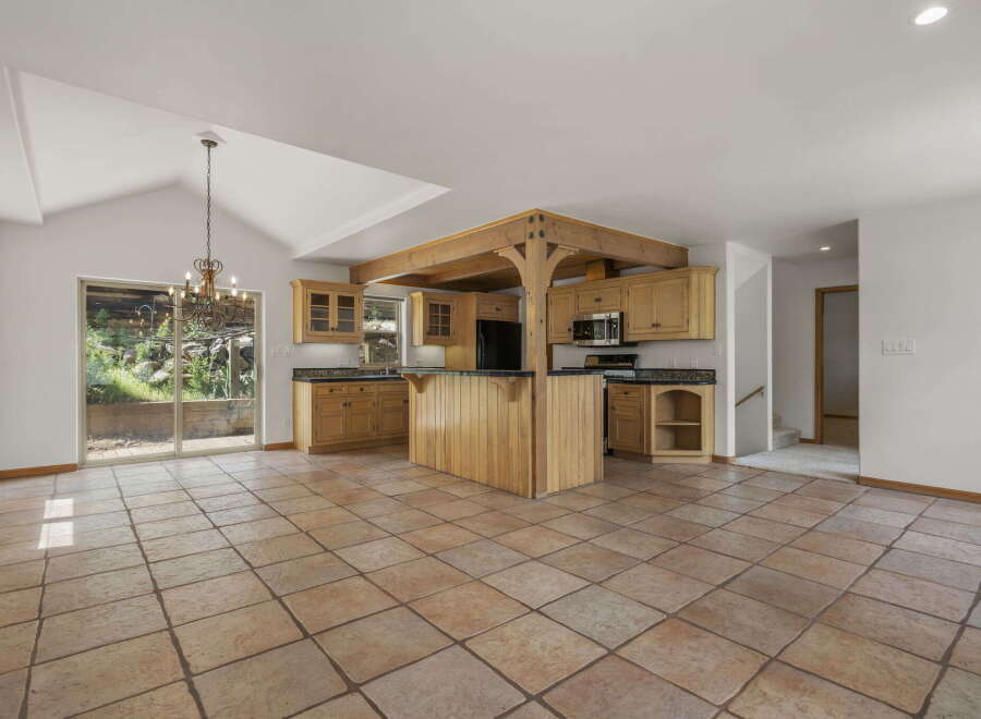 This stunning kitchen boasts a unique design with a central island and wooden beams, creating a warm and inviting atmosphere.