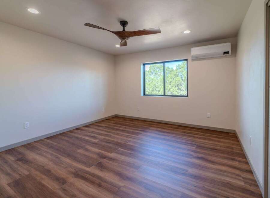 Step into this inviting bedroom featuring stunning wood-look flooring and a modern ceiling fan.