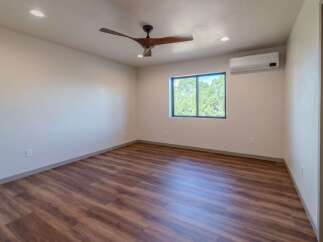 Step into this inviting bedroom featuring stunning wood-look flooring and a modern ceiling fan.
