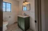 This stunning bathroom features a modern design with a sleek green vanity and a stylish black faucet.