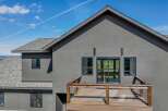 This stunning modern home boasts a sleek, gray exterior and a spacious wooden deck, perfect for enjoying the outdoors.