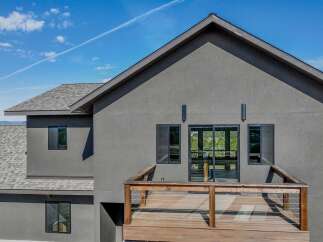 This stunning modern home boasts a sleek, gray exterior and a spacious wooden deck, perfect for enjoying the outdoors.