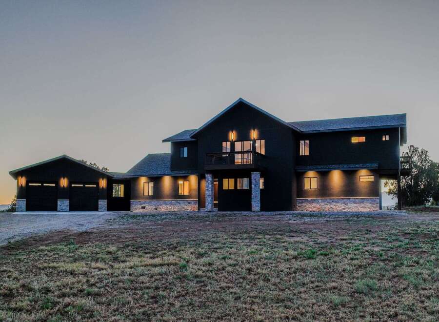 This stunning modern home boasts a sleek, dark exterior and a spacious design.