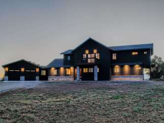 This stunning modern home boasts a sleek, dark exterior and a spacious design.