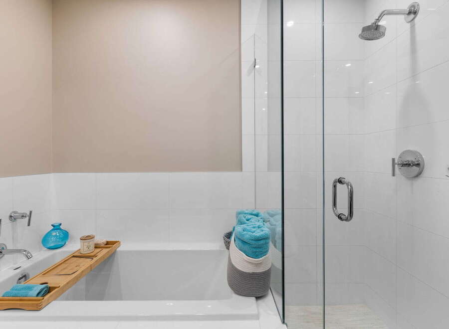 Step into luxury with this stunning bathroom featuring a sleek glass shower and a relaxing bathtub.