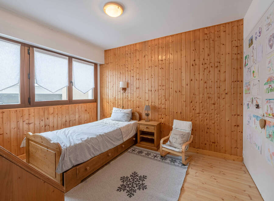 Discover the charm of this cozy bedroom featuring warm wooden paneling and a comfortable single bed.