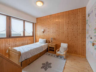 Discover the charm of this cozy bedroom featuring warm wooden paneling and a comfortable single bed.