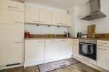 This modern kitchen boasts sleek, cream-colored cabinetry and a functional layout, perfect for culinary enthusiasts.