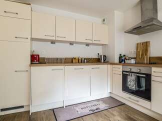This modern kitchen boasts sleek, cream-colored cabinetry and a functional layout, perfect for culinary enthusiasts.