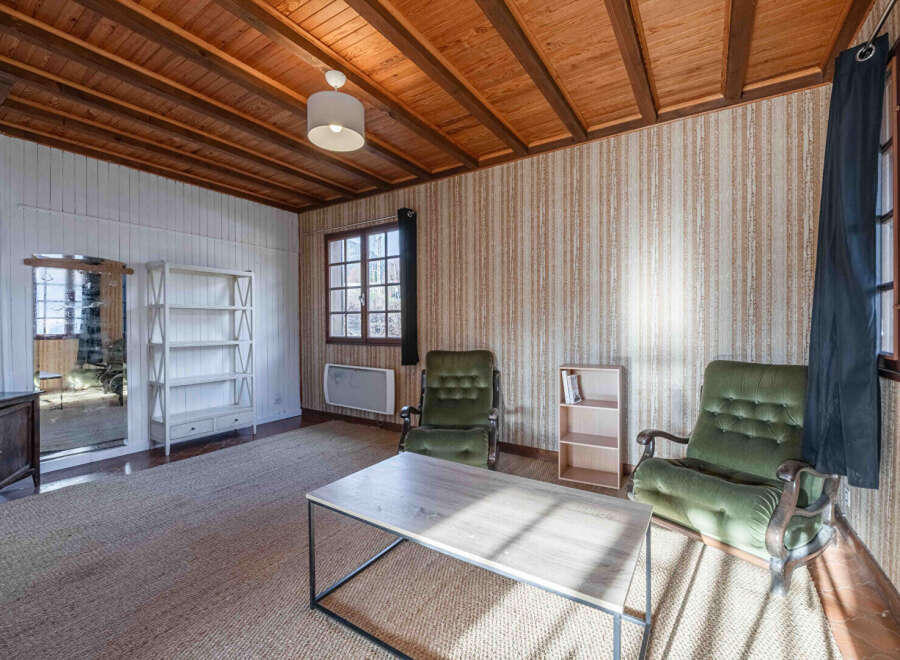 Discover the charm of this inviting living space, featuring a cozy ambiance with its wooden ceiling and textured wallpaper.
