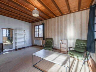 Discover the charm of this inviting living space, featuring a cozy ambiance with its wooden ceiling and textured wallpaper.