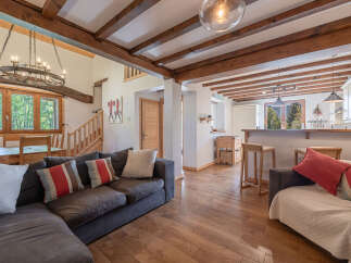 Step into this stunning property featuring a cozy living area with a comfortable sectional sofa and a beautiful chandelier.