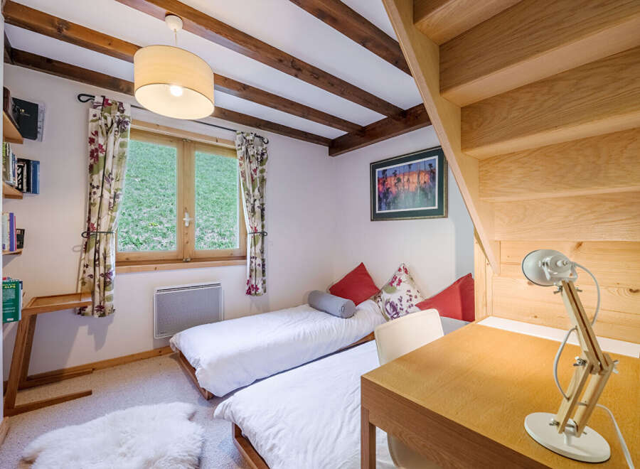 This charming bedroom features a cozy ambiance with its wooden beams and natural light.