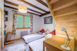 This charming bedroom features a cozy ambiance with its wooden beams and natural light.
