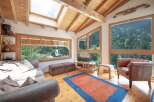 Experience the tranquility of this stunning living room, boasting panoramic views of lush greenery through expansive windows.
