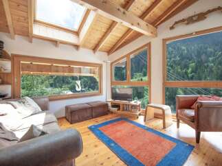 Experience the tranquility of this stunning living room, boasting panoramic views of lush greenery through expansive windows.