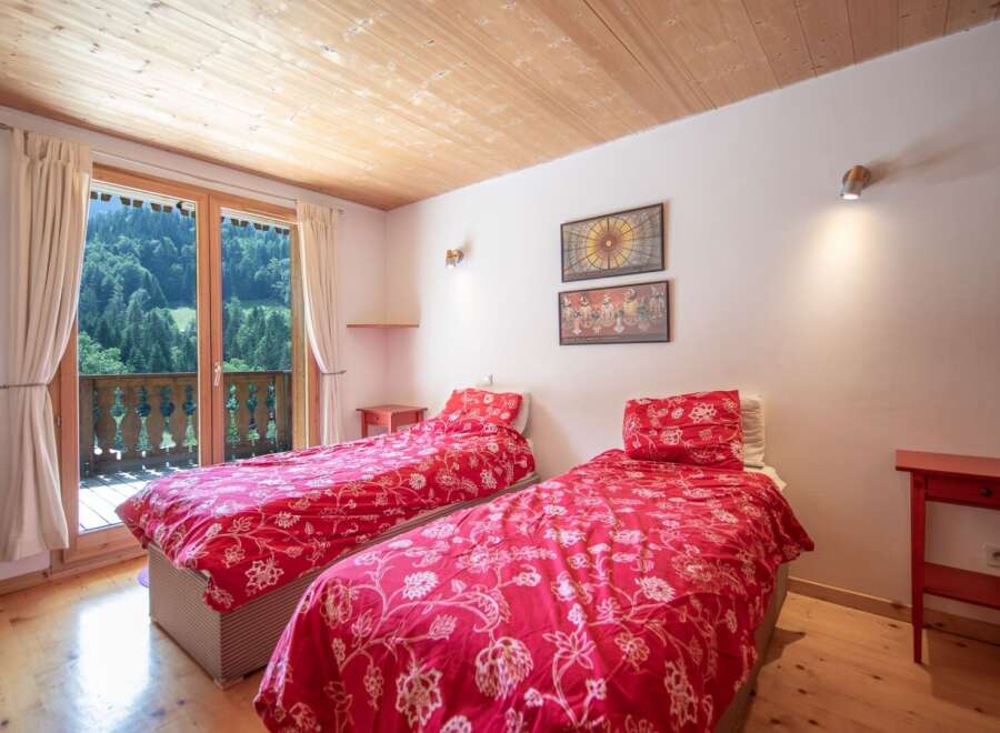 This charming bedroom features two twin beds with vibrant red floral bedding, creating a cozy and inviting atmosphere.