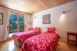 This charming bedroom features two twin beds with vibrant red floral bedding, creating a cozy and inviting atmosphere.