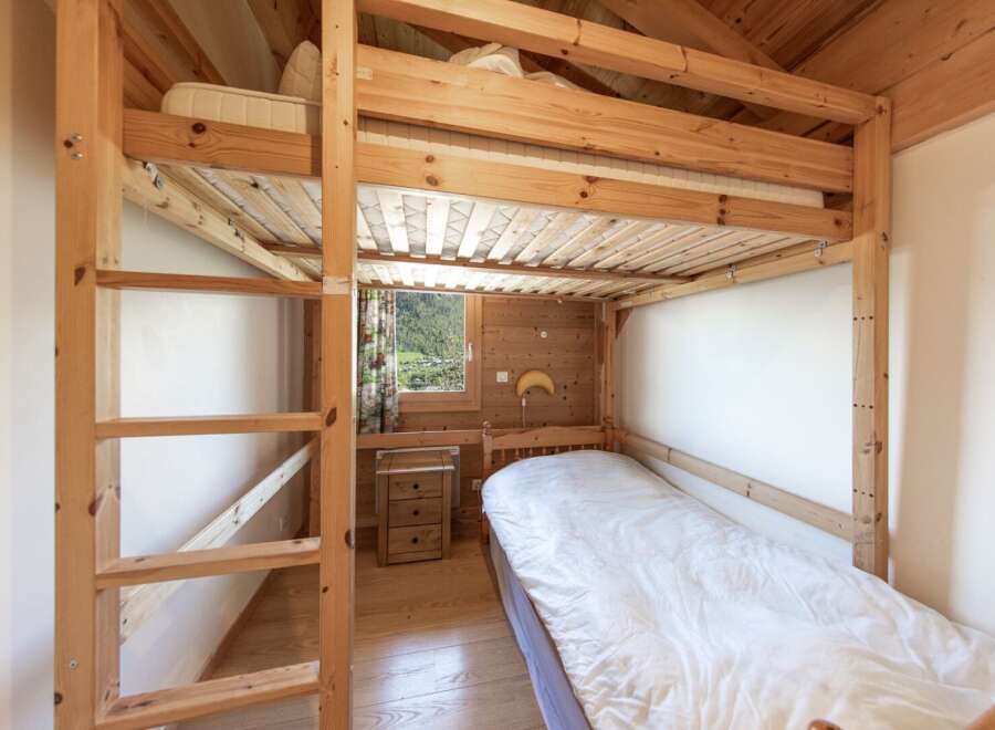 Discover the charm of this cozy bedroom featuring a unique wooden bunk bed, perfect for maximizing space.