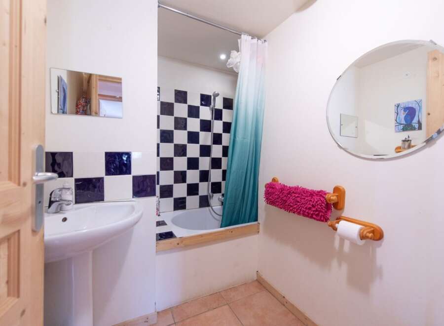 Discover this charming bathroom featuring a unique black and white checkered tile design, creating a stylish and modern aesthetic.