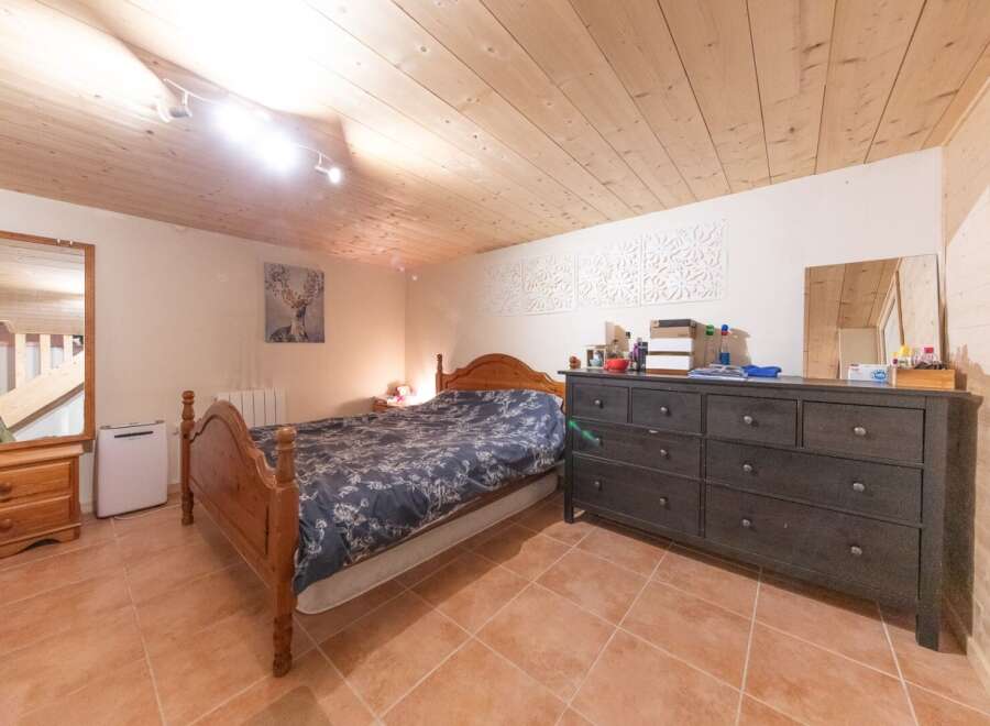 Discover the charm of this cozy bedroom featuring a wooden bed frame and a stylish dresser.