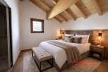 Experience luxury in this stunning bedroom featuring a cozy bed, elegant bench, and a warm, inviting atmosphere.