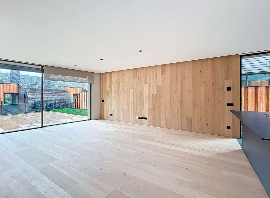 This modern living space boasts a stunning wooden accent wall and light-colored hardwood floors, creating a warm and inviting atmosphere.