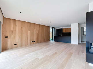 This stunning modern home features a spacious open-plan living area with beautiful light wood flooring and a feature wood-paneled wall.