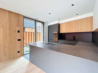This modern kitchen boasts a sleek design with a large island and integrated cooktop, perfect for culinary enthusiasts.